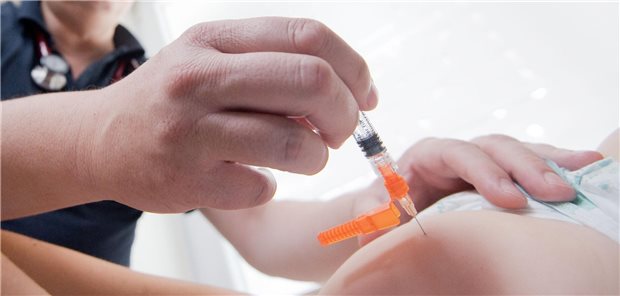 Ein Kinderarzt impft ein einjähriges Kind in den Oberschenkel gegen Masern.