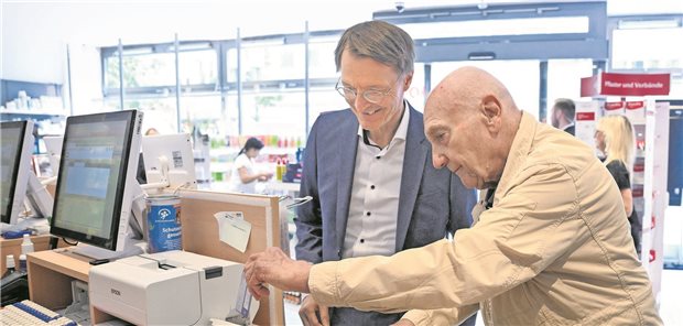 Peter Jordan, 86, steckt seine Gesundheitskarte in ein Kartenlesegerät, um in einer Apotheke Medikamente zu bekommen, die ihm verordnet worden sind. Bundesgesundheitsminister Karl Lauterbach (l, SPD) schaut bei der Präsentation des neuen Verfahrens zum Einlösen von E-Rezepten im vergangenen Sommer zu.