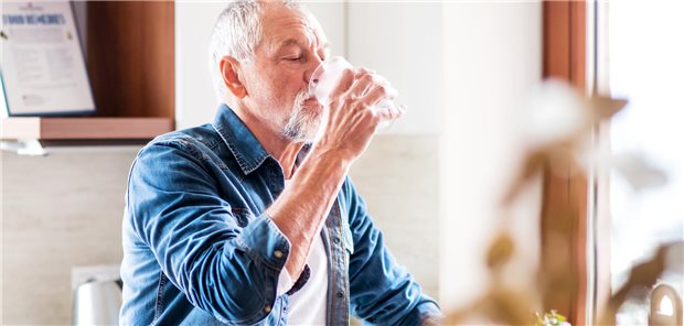 Ein älterer Mann mit weißem Vollbart trinkt aus einem Glas.