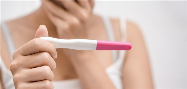 Eine Frau schaut schockiert auf ihren Schwangerschaftstest.