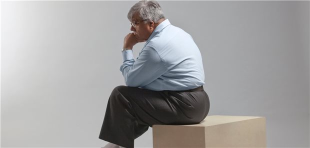Übergewichtiger Mann sitzt auf einem Hocker