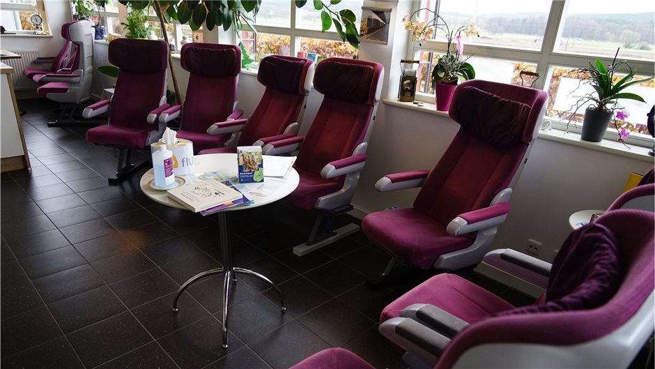  Patienten sitzen im Wartezimmer in gemütlichen ICE-Sitzen der 1. Klasse.