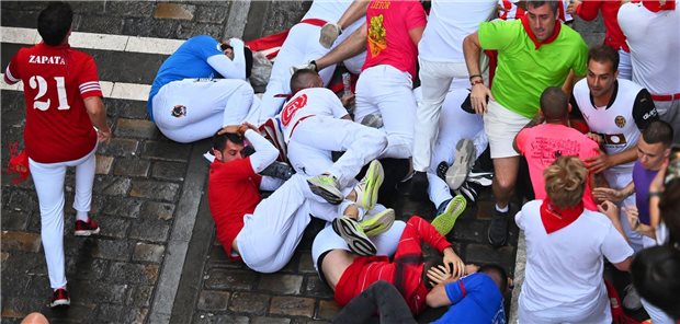 13.07.2025, Spanien, Pamplona: Teilnehmer fallen während des siebten Stiertreibens beim San-Fermín-Festival hin. Foto: Miguel Oses/AP/dpa +++ dpa-Bildfunk +++