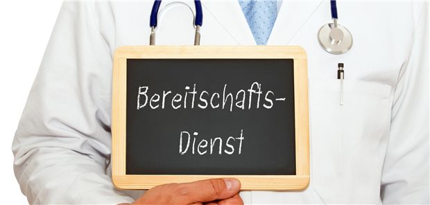 Arzt hält ein Schild mit der Aufschrift "Bereitschaftsdienst" hoch.