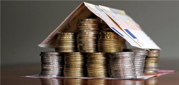 Haus aus Geldmünzen und -scheinen.