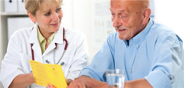 Eine Ärztin zeigt einem älteren Patienten etwas in seinem Impfpass.