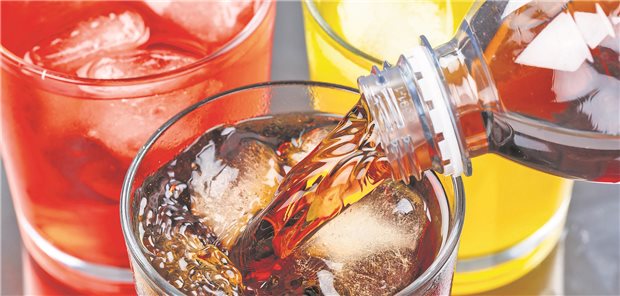 Gläser mit bunten Limonaden; in ein Glas wird eine Limonade aus einer Flasche gefüllt.