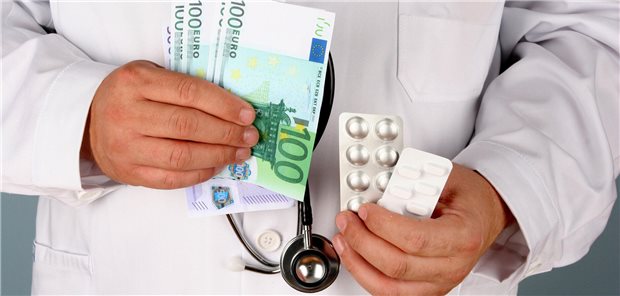 Arzt mit Geldscheinen und Tabletten