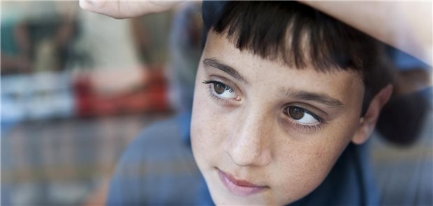 Ein Kind sieht gedankenverloren aus einem Fenster.