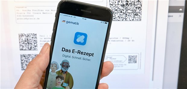 E-Rezept-App auf Handy vor einem Bildschirm