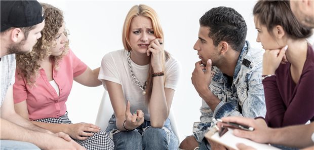 Junge Menschen trösten eine Frau.