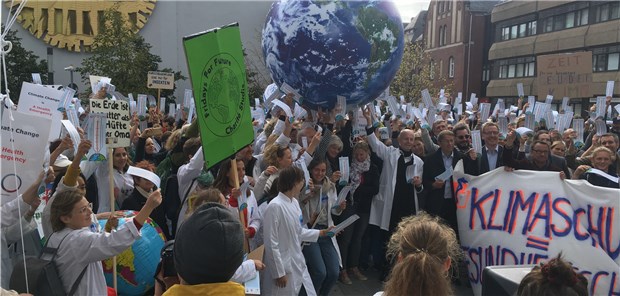 „Die Erde ist kaputter als die Hüfte deiner Oma“ Ärzte, Therapeuten und Pflegende contra Erderwärmung – hier vor der Charité in Berlin-Mitte. Mit dabei: Der ehemalige Charité-Chef Professor Detlev Ganten (Bildmitte im weißen Kittel) und der neue Präsident der Charité Professor Hayo Kroemer (rechts daneben am Banner).