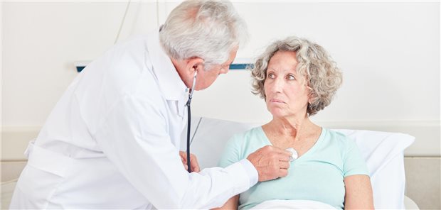 Älterer Arzt untersucht Patientin.