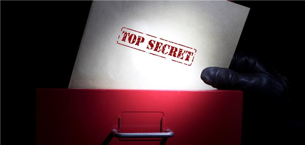 Eine Hand greift in eine Akte mit der Aufschrift &quot;Top Secret&quot;
