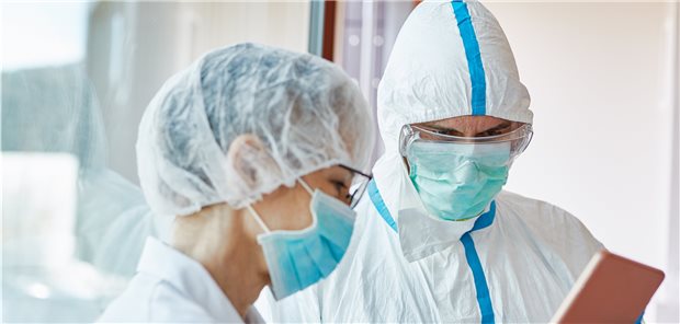 Ärzte und medizinisches Personal kommunizieren in Schutzkleidung mit COVID-19 Patienten, die häufig unter Kurzatmigkeit und Luftnot leiden. Medizinethiker haben Zweifel, ob in diesem Szenario Patienten einer Studie korrekt zustimmen können.