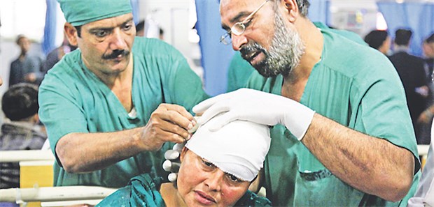 Hilfe für Erdbebenopfer ist schwierig Ärzte versorgen die Kopfwunde einer vom Erdbeben verletzten Frau in Peshawar, Pakistan.