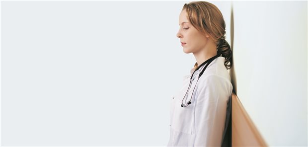 Ärztin im Stress lehnt sich an die Wand: In Krisenzeiten darf die Arbeit auch mal etwas mehr Einsatz verlangen sein, aber nicht dauerhaft. (Symbolbild mit Fotomodell).