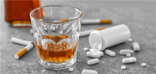 Ein Glas mit Alkohol, Zigarettenkippen und eine Dose Medikamente liegen auf dem Fußboden