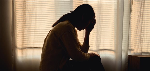 Frau greift sich im Dunkeln an den Kopf.