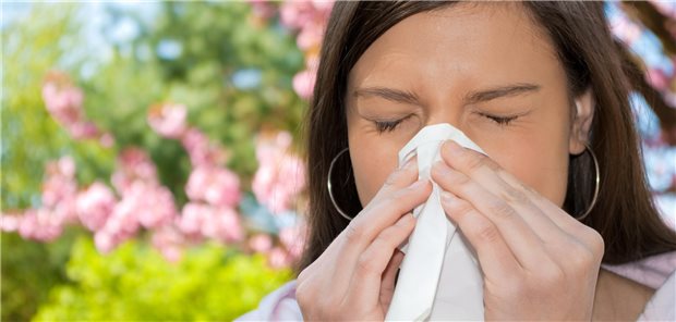 Frau mit Taschentuch beim Schnäuzen.