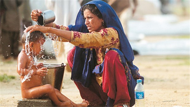 "Kinder in Pakistan verhungern - Soforthilfe muss dringend intensiviert werden" Alles verloren: Mutter wäscht Kind im Flüchtlinglager.