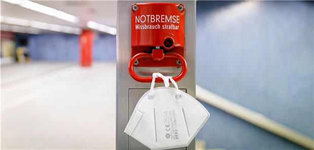 Corona: Liberale fordern Abkehr von simpler Sieben-Tage-Inzidenz An einer Notbremse in einer Bahnhaltestelle hängt eine FFP2-Maske. Mit der sogenannten Bundes-Notbremse will die Regierung die Corona-Infektionszahlen wieder nach unten drücken. Die FDP fordert nun einige Nachbesserungen.