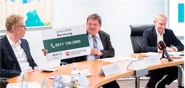 Neue Hotline für Long-COVID- und Post-Vac-Betroffene Andreas Philippi (SPD, M), Gesundheitsminister von Niedersachsen, hält ein Schild mit der Telefonnummer der Beratungsstelle in den Händen. Daneben sitzen Nils Schneider (l), Direktor des Instituts für Allgemeinmedizin an der MHH und Jürgen Peter (r), Vorstandsvorsitzender der AOK Niedersachsen.