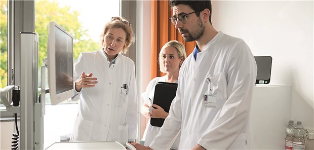 Anke Reinacher-Schick steht mit zwei Kollegen vor einem Bildschirm und begutachten ein X-Ray. 