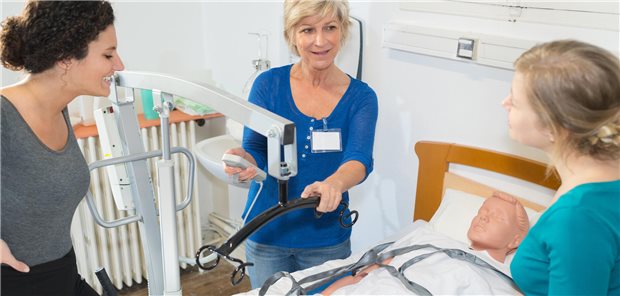 Zahl der Ausbildungsverträge in der Pflege leicht gestiegen Angehende Pflegekräfte und Dozentin stehen am Patientenbett mit Dummy.