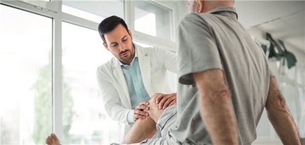 Arzt untersuch das Knie eines Patienten