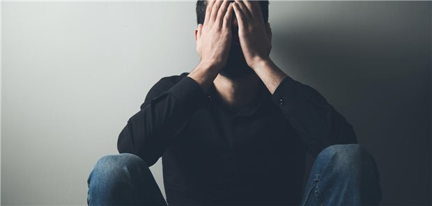 Trauriger Mann vergräbt sein Gesicht in denen Händen.