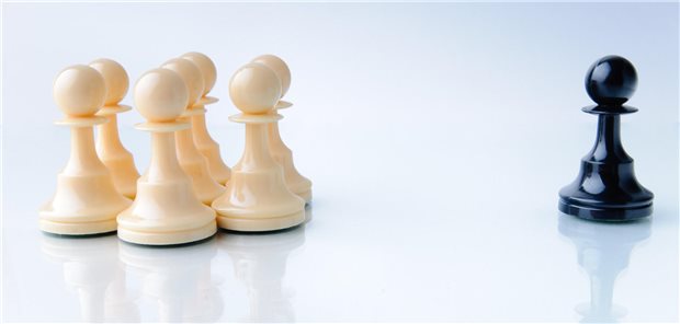 Eine Gruppe weißer Schachfiguren und eine schwarze.