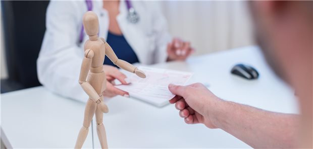 Ärztin übergibt Patienten ein Rezept.