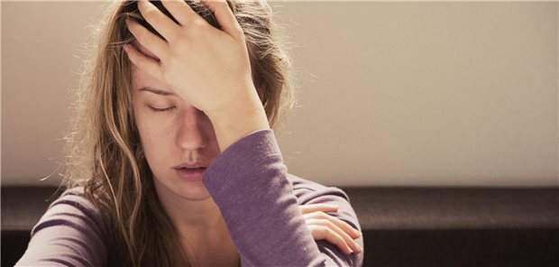 Frau hält sich die Hand an die Stirn