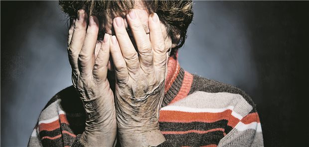 Eine Seniorin hält sich beide Hände vor ihr Gesicht.