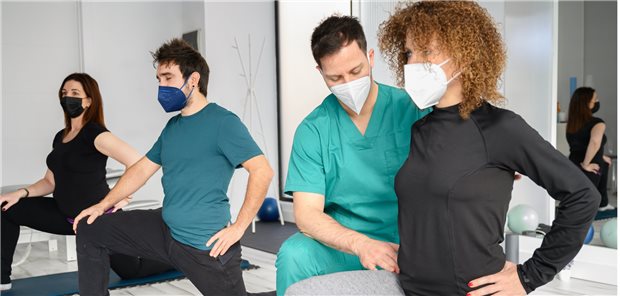 Corona und Reha: „Interdisziplinarität zahlt sich aus“ Symbolbild mit Fotomodellen: für Reha-Klinikalltag während Corona (Patienten und Physiotherapeut tragen FFP2-Masken).