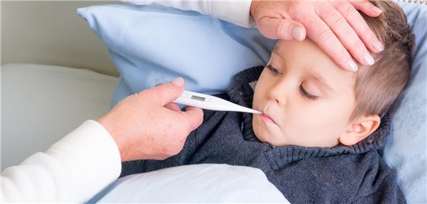 Ein Kind liegt im Bett, im Mund hat es ein Fieberthermometer.