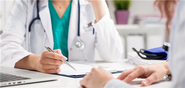 Patientin sitzt in Arztpraxis und wird von Ärztin konsultiert.