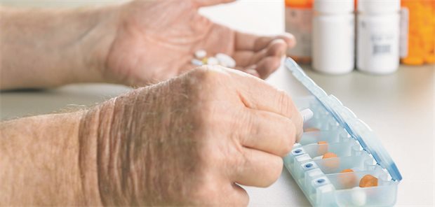 Mann vor Pillendose mit vielen Tabletten.