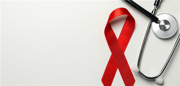 Eine Aids-Schleife liegt neben einem Stethoskop auf dem Tisch.