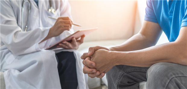 Eine Ärztin führt ein vertrauliches Gespräch mit einem jungen Mann.