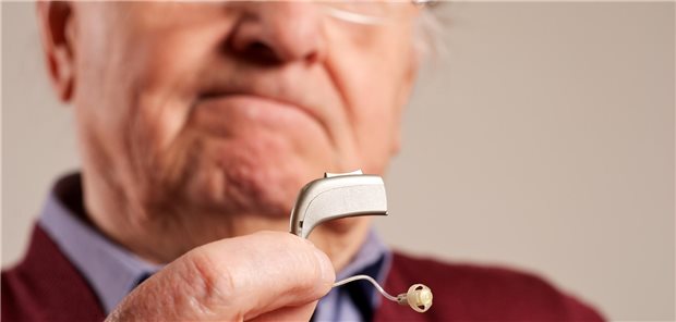 Mann mit Hörgerät in der Hand