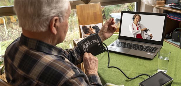 Mann misst Blutdruck und wird über Videocall angeleitet