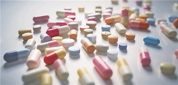 Sehr viele unterschiedliche Tabletten liegen auf einem weißen Tisch. 
