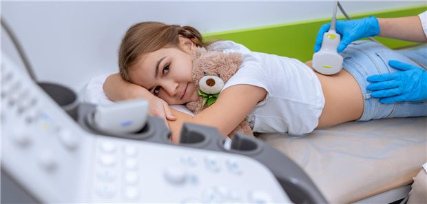 Ein Arzt führt eine Nieren-Ultraschalluntersuchung bei einem Mädchen im Schulalter durch.