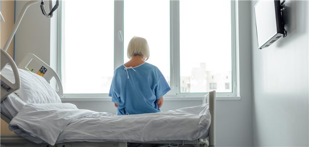 Frau sitzt im Krankenhaus mit einem Kittel.