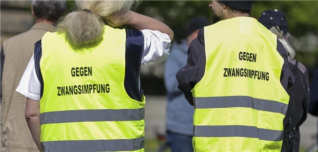 Impfgegner stehen auf der Straße.