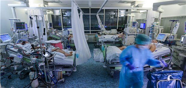 Verband fordert bessere Ausstattung zur Vermeidung von Triage Eine Intensivpflegerin versorgt Ende 2021 einen COVID-19-Patienten auf der Intensivstation der Leipziger Uniklinik in einem Zimmer, in dem noch drei weitere Corona-Patienten liegen.