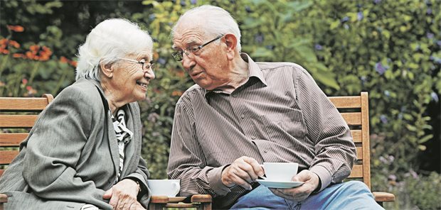 Ein älteres Paar sitzt mit Kaffee draußen.