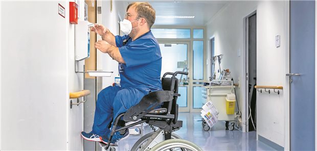 Bevor es zur Patientin in den Schockraum geht, fährt Leopold Rupp seinen Arbeitsrollstuhl hoch und desinfiziert sich die Hände.